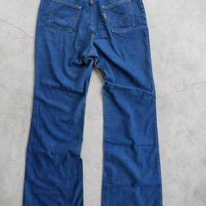 May include: A pair of blue denim jeans with a classic five-pocket design. The jeans feature a high waist, a straight leg, and the Levi's brand label on the back. The jeans are made of a durable denim fabric.
