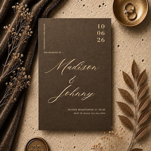 May include: A rectangular dark brown wedding invitation card with gold lettering reading Madison & Johnny, the date 10 06 26, and event details. The card is surrounded by brown velvet fabric, dried flowers, a gold bowl with two rings, and a wax seal.