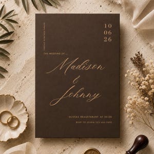 Può includere: Un invito di nozze rettangolare color marrone scuro con scritte in lamina d'oro. Il testo recita: Together with their families, The wedding of Madison & Johnny, 10 06 26, Olivias Reaustarant at 20:00, RSVP to Olivia 123-456-7890.