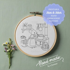 Peut inclure: Un tambour à broder en bois rond contenant un tissu blanc avec un dessin au trait noir représentant une souris portant un tablier et cuisinant sur une cuisinière. Le texte PRINTABLE Stick & Stitch HAND EMBROIDERY PATTERN est visible.