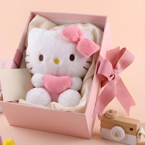 May include: A white ceramic mug with a black handle and the text "But First, Coffee" in a black, handwritten-style font. The mug is on a white surface.