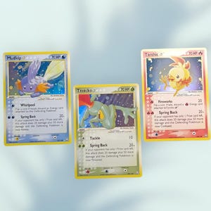 Może przedstawiać: Trzy karty kolekcjonerskie Pokémon: Mudkip, Treecko i Torchic. Karta Mudkip przedstawia niebiesko-pomarańczowe stworzenie. Karta Treecko przedstawia zielonego Pokemona przypominającego jaszczurkę. Karta Torchic przedstawia żółtego Pokemona przypominającego pisklę.