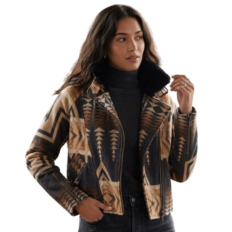 May include: A moto-style jacket featuring a brown, tan, and black geometric pattern. The jacket has a black faux fur collar, an asymmetrical front zipper closure, and zippered cuffs. It is worn over a dark gray mock neck top and dark jeans.