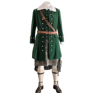 Op de afbeelding: Een donkergroene fluwelen jas met zilveren knopen, een wit overhemd met kraag, een bruine leren riem en schouderband, een grijze geruite kilt, crèmekleurige kniekousen en donkerbruine veterschoenen op een etalagepop.