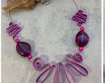Collar elegante con un original diseño de cuentas en espiral de color cereza y morado.