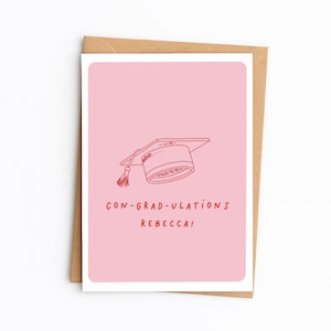Op de afbeelding: Een rechthoekige wenskaart met een lichtroze achtergrond met een rode lijntekening van een afstudeerhoed met een kwastje. Onder de illustratie staat de tekst CON-GRAD-ULATIONS REBECCA! in rode hoofdletters.
