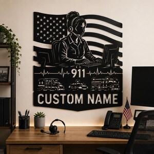 Könnte beinhalten: Ein Wandbild aus schwarzem Metall mit einem stilisierten amerikanischen Flaggenhintergrund, einem 911-Disponenten mit Headset am Computer, einer EKG-Linie, einem Krankenwagen, einem Polizeiauto, einem Feuerwehrauto sowie dem Text 911 und CUSTOM NAME.