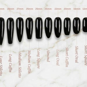 Puede incluir: Una colecci&oacute;n de u&ntilde;as postizas negras en varias formas, incluyendo Long Stiletto y Short Square. Las medidas en mil&iacute;metros se muestran encima de cada u&ntilde;a, variando de 13mm a 30mm. Las u&ntilde;as est&aacute;n dispuestas sobre una superficie con efecto m&aacute;rmol.