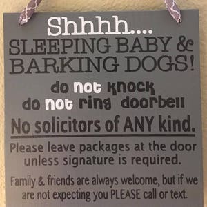 May include: A gray wooden sign with white and black text. The sign reads "Shhhh.... SLEEPING BABY & BARKING DOGS! do not knock do not ring doorbell No solicitors of ANY kind." It also includes instructions for package delivery and a welcome message for family and friends.