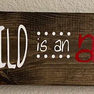 May include: A wooden sign with the text "EVERY CHILD is an artist - Pablo Picasso -" in white lettering. The word "artist" is spelled out in rainbow colors.