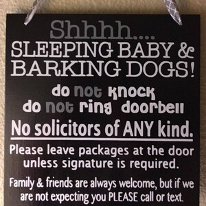 May include: Black square sign with white text that reads "Shhhh.... SLEEPING BABY & BARKING DOGS! do not knock do not ring doorbell No solicitors of ANY kind." It also says to leave packages at the door and to call or text if not expected.