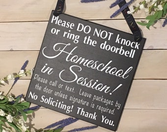 May include: Black wooden sign with white text that reads "Please DO NOT knock or ring the doorbell Homeschool in Session! Please call or text. Leave packages by the door unless signature is required. No Soliciting! Thank You."