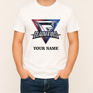 May include: A white short-sleeved t-shirt featuring a central graphic of a metallic triangular emblem with red and blue lighting effects. The word GLADIATORS is printed in a bold, stylised font across the emblem, with the text YOUR NAME below.