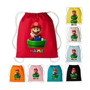May include: Red drawstring bag with a Mario graphic emerging from a green pipe. The word "NAME" is printed below the character in a colourful font. Other drawstring bags in yellow, white, blue, orange, pink, teal, and black are also shown.
