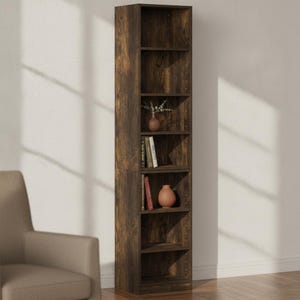 May include: A tall, narrow, dark brown wood-grain bookshelf featuring six open storage compartments. The shelves contain a small vase with greenery, several books, and a rounded decorative object, with pre-drilled holes visible along the interior sides.