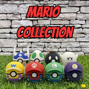 May include: A collection of colorful Mario-themed character figures, including characters like Mario, Luigi, and Wario. The figures are displayed on a bed of green grass in front of a stone wall. The words "MARIO COLLECTION" are written in red.