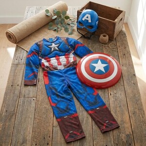 May include: A Captain America costume set, including a blue and red jumpsuit, a shield, and a blue helmet with a white "A" on it. The costume is displayed on a wooden surface.