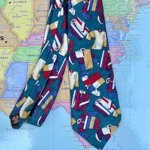May include: A teal blue silk tie with a repeating pattern of colorful athletic jerseys. The jerseys are in various colors, including red, white, blue, yellow, and purple.
