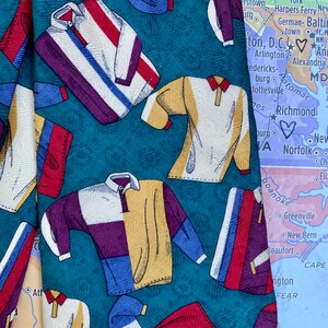 May include: A teal blue silk tie with a repeating pattern of colorful polo shirts. The tie is partially obscured by a map of the eastern United States.