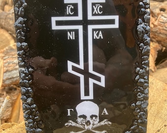 Può includere: Targa rettangolare nera con un disegno a croce ortodossa bianca e teschio con ossa incrociate. La croce ha le lettere greche IC XC NI KA. Il bordo è fatto di piccole pietre scure.