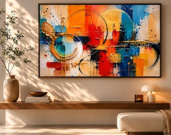 May include: Abstract art painting with a black frame. The artwork features a vibrant mix of colors, including orange, blue, red, and gold, with circular and linear shapes. The painting hangs above a wooden shelf with decor.