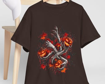 May include: A dark brown short-sleeve t-shirt featuring a graphic print of pale, skeletal hands emerging from dark foliage to hold three glowing, carved jack-o'-lantern pumpkins with bright orange light emanating from their eyes and mouths.