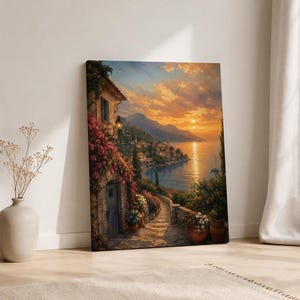 May include: A rectangular canvas print depicting a coastal Mediterranean village at sunset. The scene features a stone building covered in pink bougainvillea, a cobblestone path leading toward the sea, distant mountains, and a golden sky.