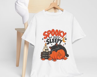 May include: A white t-shirt featuring a graphic of a black cat sleeping on an orange pumpkin. The text reads SPOOKY BUT MOSTLY SLEEPY and JUST A GIRL WHO LOVES HALLOWEEN. Below the text are books labeled PUMPKIN SPICE, HORROR MOVIES, and COZY NIGHTS.
