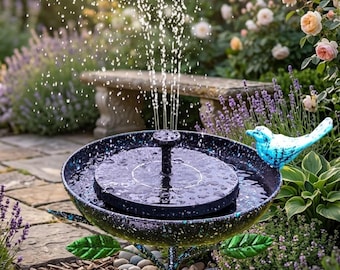 Könnte beinhalten: Solarbetriebener Gartenbrunnen mit einer schwarz gesprenkelten Schale und einem zentralen Wasserauslauf. Ein blauer Vogel-Ornament sitzt am Rand. Der Brunnen befindet sich in einem Garten mit Blumen und einer Steinbank im Hintergrund.