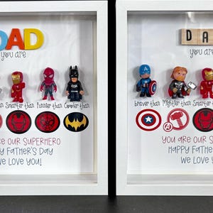 Pode incluir: Dois presentes emoldurados para o Dia dos Pais. Cada um apresenta figuras de super-heróis, logotipos e as palavras "DAD" e "You are our Superhero". O texto inclui "Happy Father's Day" e "We Love You!"