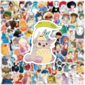 May include: A collection of anime-themed stickers featuring various characters. The central sticker showcases a gray, fluffy creature with a yellow belly, topped with two smaller blue and yellow figures, all under a green leaf.