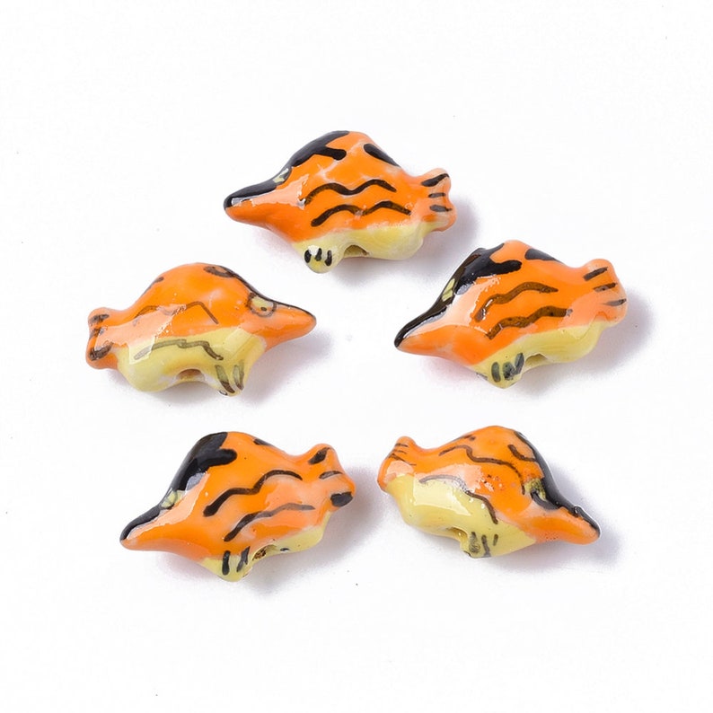 May include: Five ceramic fish beads with orange and black stripes. The beads are about 1 inch long and have a hole in the center for stringing.