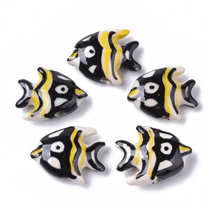 May include: Five ceramic fish beads with black, white, and yellow stripes. The fish have black eyes and are approximately 1 inch long.