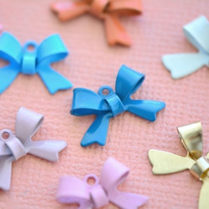 Op de afbeelding: Assortiment van kleurrijke metalen strikbedels in verschillende kleuren, waaronder blauw, paars, goud en oranje. De strikken zijn allemaal in een vergelijkbare stijl, met een eenvoudig, elegant ontwerp.