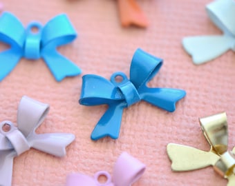 May include: Assortment of colorful metal bow charms in various colors, including blue, purple, gold, and orange. The bows are all in a similar style, with a simple, elegant design.