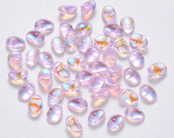 May include: A collection of iridescent pink oval glass beads. The beads have a subtle shimmer and are perfect for jewelry making or crafting.