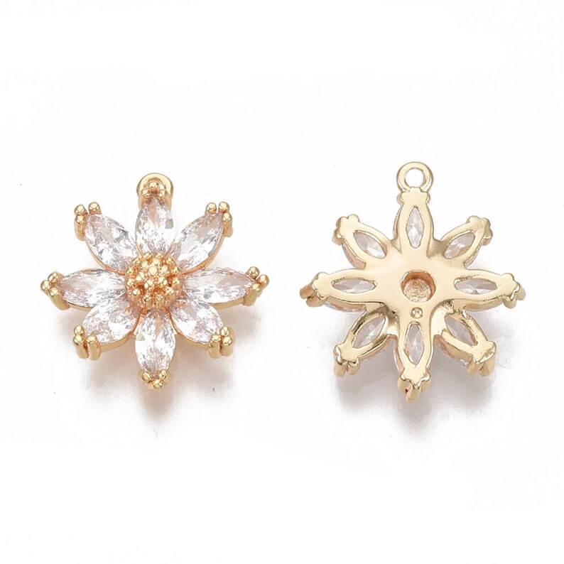 May include: A pair of gold-tone flower-shaped charms with clear crystal accents. The charms have a loop at the top for attaching to jewellery.