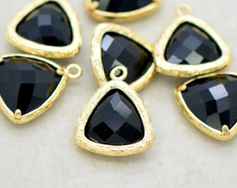 May include: A group of black triangle-shaped charms with gold-toned metal frames. The charms have a faceted design and are perfect for jewelry making.