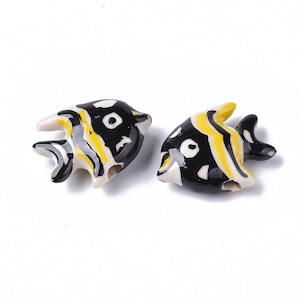 May include: Two black and yellow ceramic fish beads with white accents. The fish have black eyes and yellow stripes.