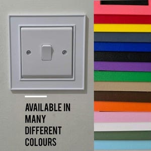 May include: A white square light switch with a central toggle and two visible screws, accompanied by a vertical color palette strip showing various shades including pink, red, yellow, blue, black, purple, green, tan, brown, orange, and white.