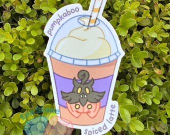 Pode incluir: Um adesivo recortado de um latte de abóbora num copo de plástico transparente com palhinha às riscas e natas batidas. O copo apresenta uma manga roxa com um gráfico de uma criatura abóbora e o texto pumpkaboo spiced latte.