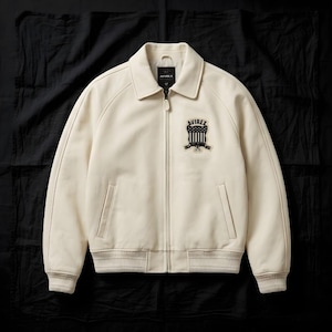 May include: Cream-coloured leather jacket with a zip-up front, collar, and ribbed cuffs and hem. Features a patch on the chest with the brand name and a shield design. The jacket has two front pockets and a classic bomber style.
