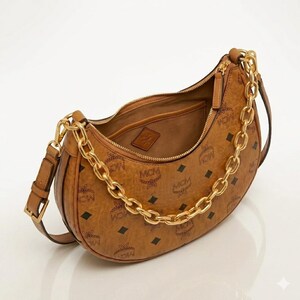 Pu&ograve; includere: Una borsa a spalla marrone con catena dorata e motivo con logo MCM. La borsa ha una forma curva, una chiusura con cerniera e una piccola tasca interna. La borsa &egrave; realizzata in materiale strutturato.