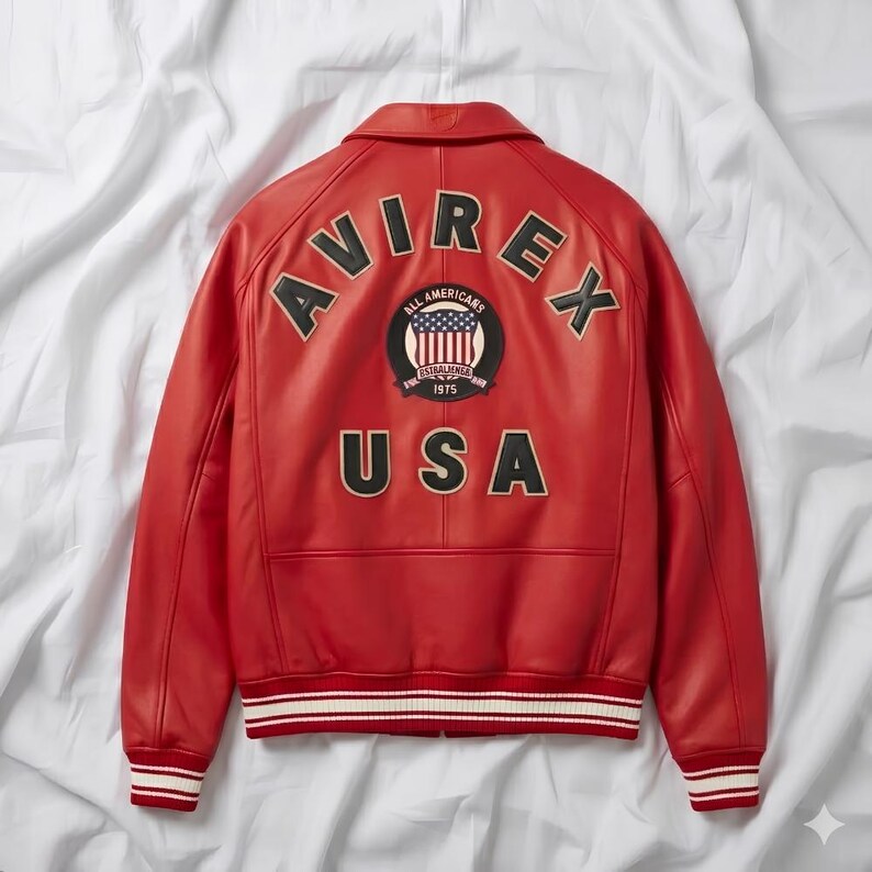 Peut inclure: Veste en cuir rouge avec le mot "AVIREX" en arc sur les &eacute;paules. En dessous, un &eacute;cusson avec les mots "ALL AMERICANS" et "ESTABLISHED 1975". Le mot "USA" est en dessous. La veste a une bordure ray&eacute;e blanche et rouge.