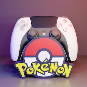 May include: A white and black wireless video game controller featuring a central PlayStation logo, positioned behind a circular red, white, and blue emblem with the yellow text Pokémon written in a stylized font across the bottom section.