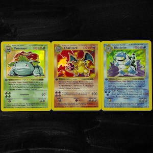 May include: A set of three ceramic mugs with a speckled, matte finish. The mugs are in shades of cream, light gray, and dark gray. Each mug has a simple, minimalist design and a rounded handle.