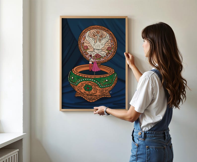 Woman hanging a framed Anastasia-inspired music box print on a white wall—romantic printable art for animation fans.