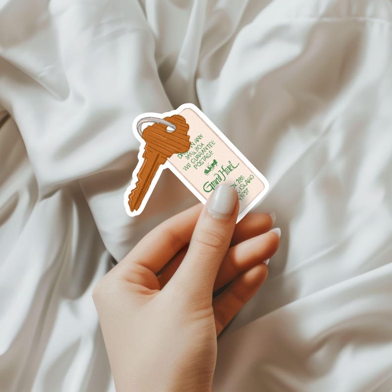 May include: A sticker of a brown key and a hotel key tag. The tag reads "Grand Hotel" with the address and a guarantee of postage. The key is attached to the tag with a silver ring. The sticker is held by a person.