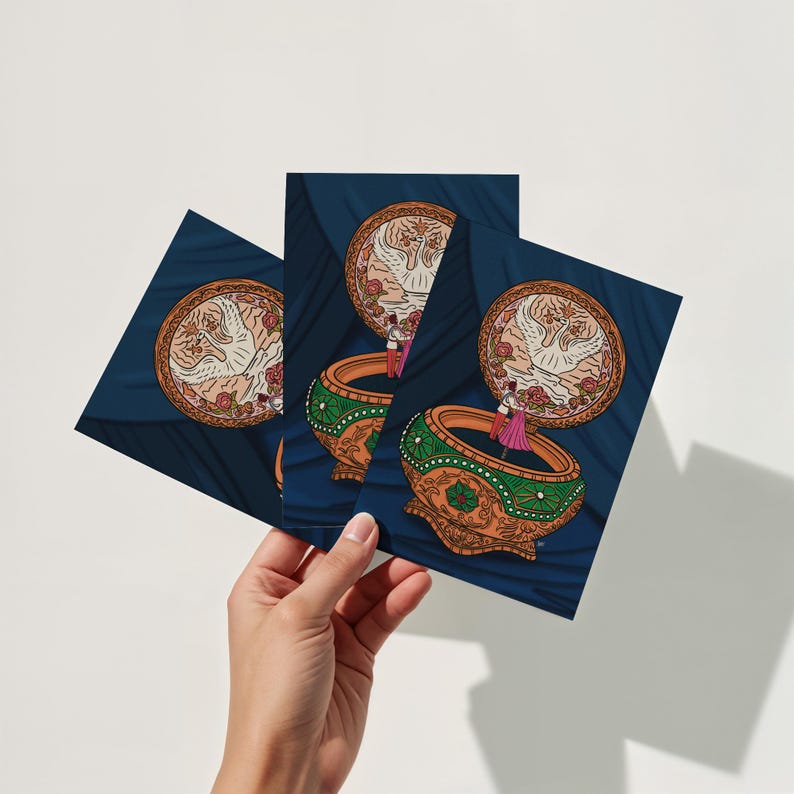 Hand holding three 5x7 art prints featuring an Anastasia-inspired music box digital illustration with romantic fairy-tale design.