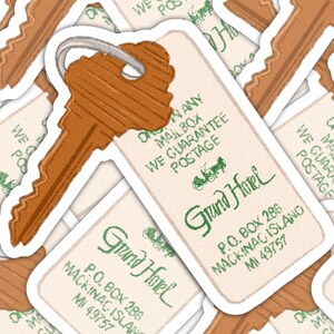 May include: A collection of stickers featuring a vintage-style key and hotel key tag. The tag reads "Grand Hotel" with the address in Mackinac Island, MI. The key and tag are brown with a white border.